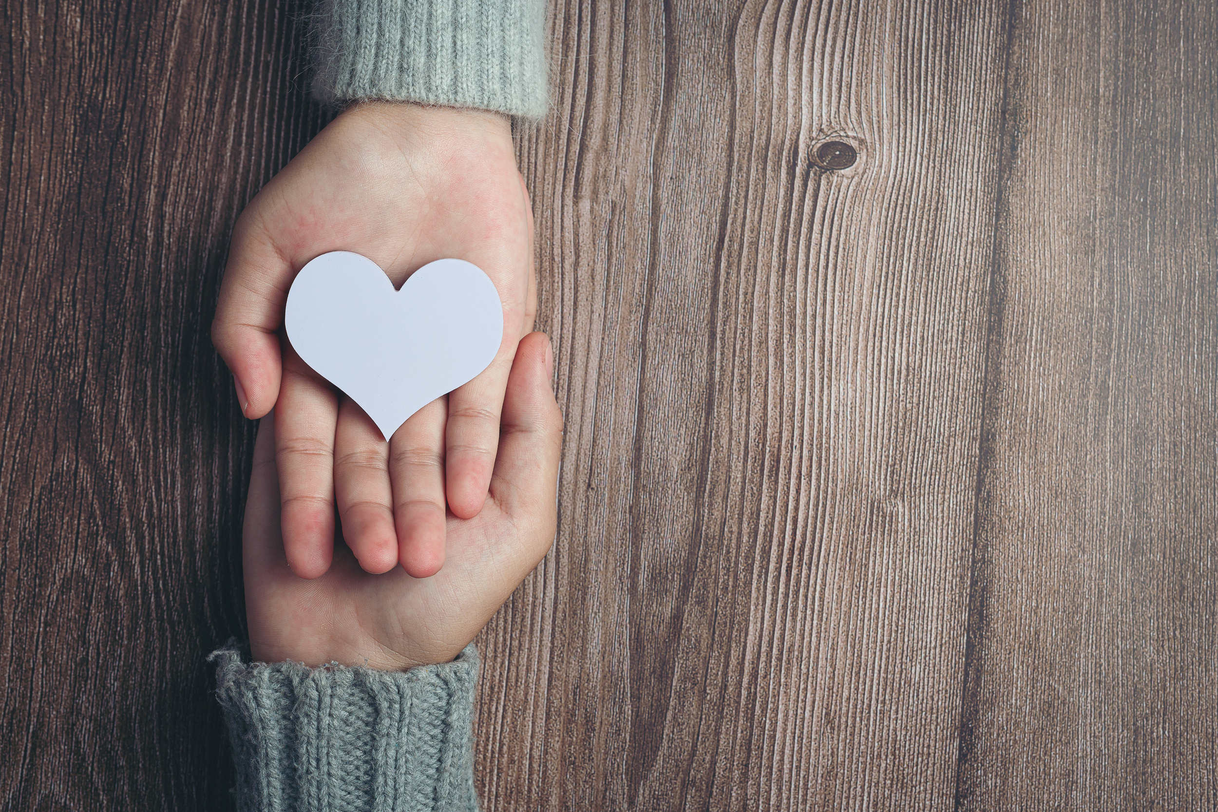 Immagine con mani e cuore bianco