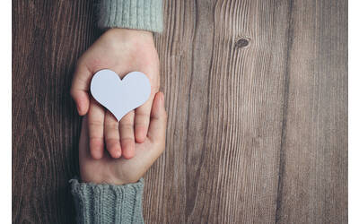 Immagine con mani e cuore bianco