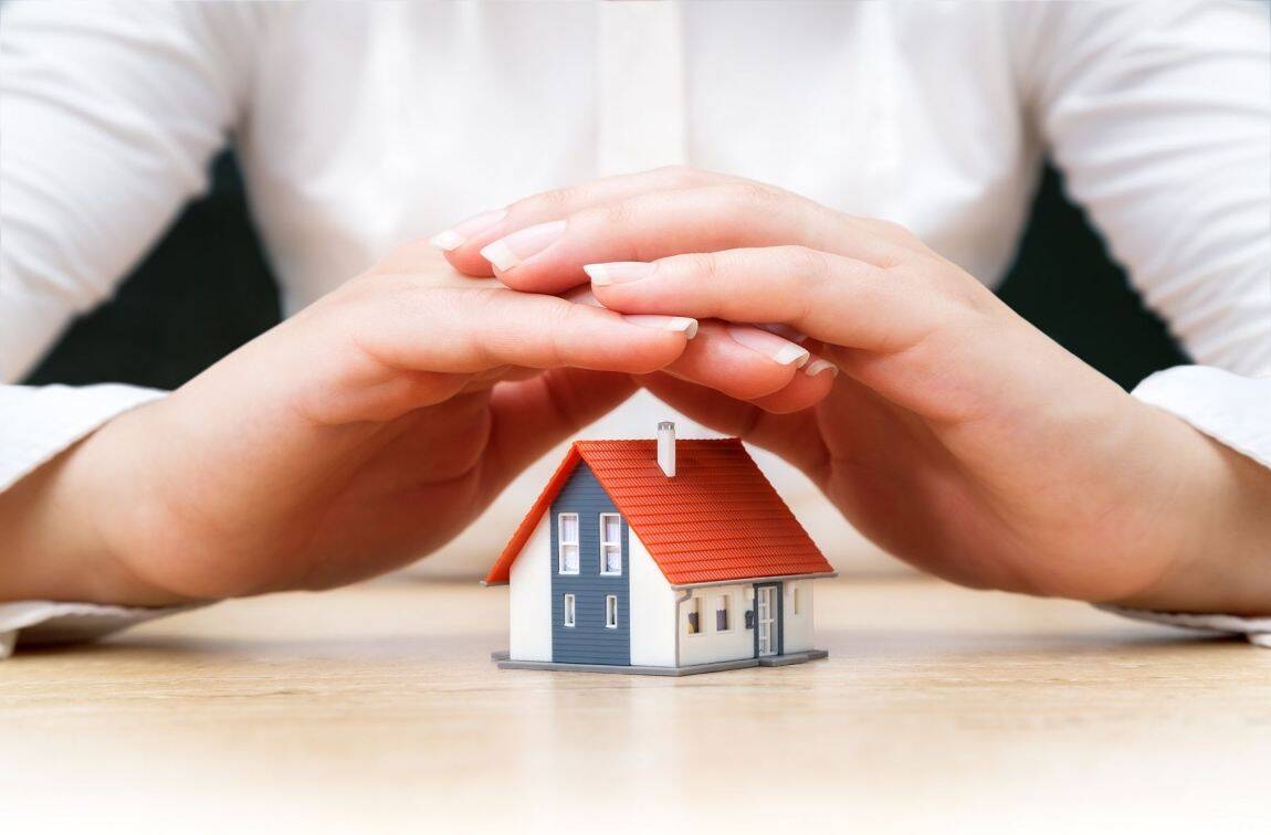immagine con mani che coprono una casetta in miniatura 